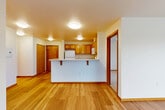 Located in Seattle's Greenwood neighborhood, this 2-bedroom, 2-bathroom residence offers a thoughtfully designed single-level layout that maximizes comfort and functionality. The open-concept living, dining, and kitchen area serves as the heart of the home, featuring warm hardwood-style flooring, bright white walls, and wood trim that lend a clean, cohesive aesthetic throughout. Large windows flood the living room with natural light and frame views of the surrounding neighborhood, while a sliding door leads to a private balcony. The kitchen is equipped with warm-toned wood cabinetry, white appliances including a refrigerator, electric range, microwave, and dishwasher, and a peninsula with a light stone countertop that provides both prep space and casual seating. Both bedrooms are carpeted and offer a calm, restful atmosphere. The primary bedroom includes a mirrored sliding-door closet and a window with neighborhood views. The bathrooms feature wood-cabinet vanities, stone-top counters, and hardwood-style flooring consistent with the rest of the home. Four closets throughout provide generous storage. The overall ambiance is bright, functional, and move-in ready.