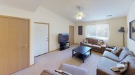 Located at 401 Russell Rd in DeKalb, Illinois, this single-floor unit offers a well-organized layout designed for practical, comfortable living. The expansive living room is a welcoming centerpiece, featuring soft carpeting, a ceiling fan with light fixture, and large windows that invite natural light throughout the space. The room comfortably accommodates multiple seating arrangements, making it ideal for both relaxing and entertaining.

The kitchen is efficiently designed with ample white cabinetry trimmed in warm wood tones, generous counter space, and a full suite of appliances including a range, microwave, and dishwasher. Light-toned flooring adds brightness to the space, which also includes a dedicated dining area.

The unit features multiple bedrooms, each carpeted and finished with neutral walls. Bedrooms vary in size, with some offering windows with outdoor views and others providing dual closet access for enhanced storage. The layout from the dollhouse view reveals a thoughtfully arranged floor plan with clear separation between living and sleeping areas.

Bathrooms are well-appointed with granite-style countertops, large mirrors, and recessed lighting. Notably, one bathroom includes an in-unit washer and dryer, adding significant convenience. Additional bathrooms feature shower-tub combinations with stylish curtains and consistent cabinetry finishes throughout.