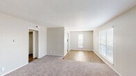 Located at 800 Custer Rd in Richardson, TX, this single-story 2-bedroom, 1-bathroom home offers a thoughtfully designed layout with a clean, neutral aesthetic throughout. The living area seamlessly transitions between plush carpet and wood-look vinyl flooring, creating a warm and inviting atmosphere. Large windows dressed with horizontal blinds allow generous natural light to fill the space, with views of the surrounding neighborhood.

The kitchen is a standout feature, boasting white shaker-style cabinetry, light quartz countertops, a gray subway tile backsplash, and a skylight that bathes the galley-style space in natural light. Black appliances, including a refrigerator, range, microwave, and dishwasher, provide a bold contrast against the bright cabinetry and wood-look floors.

The spacious primary bedroom offers generous proportions with soft carpet flooring, a ceiling fan with light fixture, and a sliding-door closet. The second bedroom also features carpet flooring and a large window that invites ample natural light. A dedicated closet adds convenient storage to the layout.

The bathroom is finished with wood-look flooring, a white vanity with quartz countertops, a tiled shower-tub combination, and overhead cabinetry for additional storage. Clean, simple finishes carry a cohesive and practical design throughout this comfortable Richardson home.