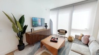 Located at 700 W 9th St in the heart of downtown Los Angeles, this single-floor residence offers a thoughtfully designed layout with modern finishes and a cohesive contemporary aesthetic throughout.

The open-concept living area is bright and welcoming, bathed in natural light through floor-to-ceiling windows fitted with roller shades. The space is anchored by a slatted wood media credenza, a sculptural wood coffee table, and a plush sectional sofa, all set atop an artfully patterned area rug that adds warmth and character.

The kitchen is a standout feature, boasting a generous quartz waterfall island with an undermount sink, taupe flat-front cabinetry, a white tile backsplash, and a full suite of stainless steel appliances including a gas range and refrigerator. Pendant lighting adds a polished finishing touch.

Two bedrooms provide comfortable retreats. The primary bedroom features a warm blush accent wall, hardwood-style flooring, large windows with city views, and access to a walk-in closet. The second bedroom offers expansive glazed sliding doors that fill the room with natural light and urban views. The bathroom is clean and functional, with a soaking tub, wood-toned built-in shelving, and quartz countertops. Hardwood-style flooring runs throughout, tying the entire residence together seamlessly.