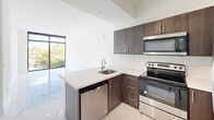 Located at 1 Curtiss Pkwy in Miami Springs, FL, this modern 2-bedroom, 1-bathroom residence offers a clean, contemporary design throughout. Polished marble-look porcelain tile floors flow seamlessly across every room, reflecting natural light and creating a bright, airy atmosphere.

The kitchen is a standout feature, equipped with dark espresso cabinetry, quartz countertops, stainless steel appliances including a range, microwave, dishwasher, and refrigerator, and a peninsula with a built-in sink — ideal for both everyday cooking and entertaining.

The spacious primary bedroom offers generous proportions, a large closet, and access to the full bathroom. The second bedroom benefits from floor-to-ceiling windows that frame lush outdoor views, flooding the space with natural light. The bathroom continues the marble aesthetic with matching tile on both the floors and shower walls, paired with a modern vanity.

Additional highlights include a dedicated in-unit laundry room with a full-size washer and dryer, a hallway connecting all rooms efficiently, and elevated ceilings in the main living area that enhance the sense of openness. The layout is practical and well-organized, making the most of the available space throughout.