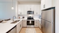 Located at 215 Florida St in Knoxville, TN, this thoughtfully designed one-bedroom, one-bathroom residence offers a clean, modern aesthetic throughout its efficiently laid-out single floor. The open-concept kitchen and living area serves as the heart of the home, where white shaker cabinetry with matte black hardware pairs seamlessly with white quartz countertops and a full suite of stainless steel appliances, including a refrigerator, range, microwave, and dishwasher. A peninsula with pendant lighting and bar seating provides an ideal space for casual dining and entertaining. Light hardwood flooring flows throughout the unit, enhancing the bright, airy atmosphere created by crisp white walls and recessed lighting. The living area is bathed in natural light from large windows and is accented by a ceiling fan. The bedroom offers a comfortable, well-proportioned retreat with natural light from a window, ceiling fan, and direct access to a spacious walk-in closet outfitted with wire shelving systems for versatile organization. The bathroom features a white vanity with quartz countertop, a multi-globe light fixture, and a walk-in shower. A dedicated laundry area adds everyday convenience, rounding out this well-appointed Knoxville residence.