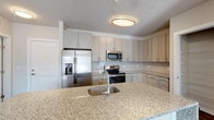 Located at 7740 Midtown Market Avenue in Raleigh, NC, this single-floor residence offers a thoughtfully designed open layout with contemporary finishes throughout. The kitchen serves as a central highlight, featuring light wood cabinetry with a subtle linear grain, a subway tile backsplash, stainless steel appliances including a refrigerator with ice and water dispenser, electric range, and microwave, along with a generously sized granite island with an undermount sink — ideal for both meal preparation and casual dining. Track and flush-mount lighting illuminate the space effectively.

Hardwood-style flooring extends throughout the main living areas, complementing the neutral gray-toned walls. The living area receives ample natural light through French doors that open to an outdoor area, and a ceiling fan adds comfort to the space. Multiple bedrooms feature large windows that allow sunlight to pour across the floors, creating a bright and welcoming atmosphere.

The bathrooms are well-appointed, one featuring a double-sink vanity with granite countertops and a tub-shower combination with tile surround, and another with a glass-enclosed walk-in shower and matching cabinetry. A dedicated laundry room with full-size washer and dryer and overhead shelving adds practical convenience to this well-finished residence.