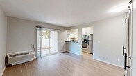 Located at 3644 Kings Way in Sacramento, CA, this one-bedroom, two-bathroom unit offers a well-organized single-floor layout designed for efficient, comfortable living. The combined kitchen and living area forms the heart of the space, featuring light wood-style flooring, neutral gray walls, and a sliding glass door that opens to a private patio, filling the room with natural light. A wall-mounted PTAC unit provides individual climate control. The kitchen is outfitted with white cabinetry, dark countertops, stainless steel appliances including a refrigerator, microwave, and range, and a peninsula that provides a natural divide between the kitchen and living areas. A barn-style door leads toward the bedroom corridor, adding a modern design touch. The bedroom is a cozy, well-proportioned room with a window that brings in natural light and views of the surrounding outdoor greenery. The unit includes two bathrooms: one featuring a full tub-shower combo with clean white finishes, and a second with a white vanity, built-in shelving, and a separate toilet area. A dedicated closet provides additional storage. The overall aesthetic is clean, modern, and move-in ready.