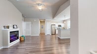 Located at 198 Mill Bayou Blvd in Lynn Haven, FL, this two-story, two-bedroom, two-bathroom home offers a well-designed layout spread across two floors. The main living level features an open-concept living and kitchen area with vaulted ceilings and a ceiling fan, creating an airy, spacious atmosphere. Wide-plank wood-style flooring flows throughout the main level, complemented by neutral wall tones and abundant natural light from multiple windows. A standout electric fireplace with a white mantle anchors the living room, adding warmth and character to the space. The kitchen is equipped with stainless steel appliances, white cabinetry, granite countertops, and a peninsula breakfast bar illuminated by pendant lighting — ideal for casual dining and entertaining. A staircase with white-painted treads leads to the upper floor, where both bedrooms are located. The bedrooms feature plush carpeting, ample closet space with wire shelving systems, and windows that bring in natural light. The bathrooms are finished with wood-style flooring, white vanities, granite countertops, and well-lit mirrors. Hallways connect each area efficiently, and two closets provide generous storage throughout the home.