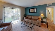 This single-floor residence offers a thoughtfully designed layout that balances functionality and comfort across its key living spaces. The living room serves as the heart of the home, featuring plush carpeting, a bold teal accent wall, and a sliding glass door that welcomes natural light and provides outdoor views — creating a warm, inviting atmosphere. Adjacent to the living room, the dining area accommodates a full dining table beneath a multi-light chandelier, with louvered closet doors adding a classic architectural touch.

The kitchen is efficiently arranged with gray cabinetry, a mosaic tile backsplash, laminate countertops, and a full suite of black appliances including a refrigerator, dishwasher, and range. Wood-look flooring ties the kitchen and adjacent spaces together seamlessly.

The primary bedroom features soft carpeting, a serene color palette, and a walk-in closet, offering a restful retreat. The second bedroom mirrors this comfort with carpet flooring, a built-in closet with louvered doors, and a window that invites natural light. Both bathrooms are consistently finished with gray vanity cabinetry, stone-tone countertops, wood-look flooring, and well-lit vanity mirrors, providing a clean and cohesive aesthetic throughout.