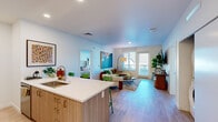 Located at 9950 NE Gibbs Dr in Hillsboro, Oregon, this 2-bedroom, 2-bathroom residence offers a thoughtfully designed single-floor layout. The open-concept living and kitchen area serves as the heart of the home, where light wood-look flooring and crisp white walls create a bright, contemporary atmosphere. Large windows in the living room invite abundant natural light and provide views of the surrounding neighborhood.

The kitchen features wood-toned flat-front cabinetry, white quartz countertops, stainless steel appliances, and a peninsula with an undermount sink — offering both functionality and a clean aesthetic. The space flows seamlessly into the living area, making it ideal for everyday living.

Both bedrooms are well-proportioned and serene, with the primary bedroom offering a walk-in closet with wire shelving and direct access to a full bathroom. The second bedroom is equally comfortable, benefiting from natural light through a large window. Each bathroom features light wood flooring and clean, minimalist finishes.

Additional highlights include dedicated closets in both bedrooms, an in-unit laundry area, and recessed lighting throughout. The overall design balances modern finishes with a warm, livable feel, making this a functional and attractive residence in the Hillsboro community.