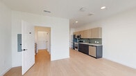 Located at 700 Hamilton Ave in Nashville, TN, this thoughtfully designed one-bedroom, one-bathroom unit offers a clean, modern aesthetic throughout. The open-concept living and kitchen area is bathed in natural light from tall, narrow windows that frame views of the surrounding cityscape and greenery. Light hardwood flooring runs seamlessly throughout the space, enhancing the bright and airy atmosphere.

The kitchen features a galley-style layout with light wood upper cabinetry, dark lower cabinets, a sage green tile backsplash, and a full suite of stainless steel appliances including a refrigerator, range, microwave, and dishwasher. Recessed lighting and a clean countertop workspace complete the functional design.

The spacious primary bedroom is generously sized with dual windows, a ceiling fan, and ample room for furnishings. Two closets provide excellent storage, and the room connects directly to the bathroom, which includes a modern vanity, toilet, and a glass-enclosed tiled shower. Additional utility and laundry spaces round out the unit's practical offerings. The overall design emphasizes clean lines, neutral tones, and efficient use of space, making this a well-appointed urban residence in the heart of Nashville.