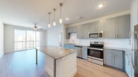 This well-appointed three-bedroom, three-bathroom residence in Little Elm, Texas offers a thoughtfully designed single-floor layout with modern finishes throughout. The kitchen is a standout feature, showcasing gray shaker-style cabinetry, granite countertops, a white subway tile backsplash, and a full suite of stainless steel appliances including a refrigerator, range, microwave, and dishwasher. A large granite-topped island with pendant lighting provides additional prep space and casual dining.

Light wood-style flooring flows seamlessly throughout the home, complementing the neutral, bright wall tones. Each bedroom is equipped with a ceiling fan and benefits from natural light through window blinds. The primary bedroom offers private balcony access with outdoor views, adding a welcoming sense of openness. Closets include built-in shelving for organized storage.

The bathrooms are finished with gray vanity cabinetry, granite countertops, and clean white tile. The primary bath features both a soaking tub and a glass-enclosed walk-in shower. Two additional closets and hallways contribute to practical circulation and storage throughout the home, making this residence as functional as it is stylish.