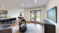 Located in Traverse City, Michigan, this single-floor residence offers a thoughtfully designed open-concept layout filled with natural light and modern finishes throughout. The living area is bright and welcoming, featuring warm hardwood-style flooring, recessed lighting, and a set of French doors that open to the outdoors, seamlessly connecting interior and exterior spaces. Adjacent to the living room, the dining area is framed by large windows overlooking a lush green landscape, creating a calm and inviting atmosphere for everyday meals. The kitchen is well-appointed with dark shaker-style cabinetry, crisp white countertops, stainless steel appliances including a refrigerator, range, and microwave, and a central island that provides additional prep space and casual seating. The bedroom is a tranquil retreat featuring plush carpeting, a stylish sliding barn door, corner windows that flood the room with natural light, and direct access to a dedicated bathroom. The bathroom is clean and functional, with wood-look flooring, a dark-toned vanity with a white countertop, and a full tub and shower combination. A utility room provides in-unit laundry hookups and additional storage. Throughout the home, crisp white walls and consistent flooring create a cohesive, contemporary aesthetic.