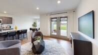 Located in Traverse City, Michigan, this single-floor residence offers a thoughtfully designed open-concept layout filled with natural light and modern finishes throughout. The living area is bright and welcoming, featuring warm hardwood-style flooring, recessed lighting, and a set of French doors that open to the outdoors, seamlessly connecting interior and exterior spaces. Adjacent to the living room, the dining area is framed by large windows overlooking a lush green landscape, creating a calm and inviting atmosphere for everyday meals. The kitchen is well-appointed with dark shaker-style cabinetry, crisp white countertops, stainless steel appliances including a refrigerator, range, and microwave, and a central island that provides additional prep space and casual seating. The bedroom is a tranquil retreat featuring plush carpeting, a stylish sliding barn door, corner windows that flood the room with natural light, and direct access to a dedicated bathroom. The bathroom is clean and functional, with wood-look flooring, a dark-toned vanity with a white countertop, and a full tub and shower combination. A utility room provides in-unit laundry hookups and additional storage. Throughout the home, crisp white walls and consistent flooring create a cohesive, contemporary aesthetic.