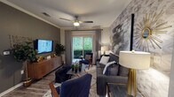 This single-story residence showcases a thoughtfully designed interior with a cohesive contemporary aesthetic throughout. The open-concept kitchen is outfitted with white shaker cabinetry, dark granite countertops, stainless steel appliances including a refrigerator, range, and built-in microwave, and a peninsula with bar seating—ideal for casual dining. Dark hardwood-style flooring flows through the main living areas, connecting seamlessly to the dining space, which features a bold navy accent wall and ample room for a full-size dining table.

The living room is a standout area, anchored by a textured geometric feature wall, a ceiling fan, and a sliding glass door that invites natural light and outdoor views. The bedroom features plush carpeting, a navy accent wall, a large window with draping, and direct access to a private en-suite bathroom. A second bathroom mirrors the design sensibility, featuring white vanity cabinetry, a single-sink vanity with a warm countertop, tile flooring, and a tub-shower combination. Both bathrooms are accented with bold-colored walls, adding a modern, curated feel that is consistent throughout this well-appointed residence.