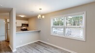 Located at 5444 Wichita Dr in Fayetteville, NC, this single-floor home presents a clean, modern aesthetic throughout its well-designed layout. The kitchen is outfitted with white shaker cabinetry, granite-style countertops, and stainless steel appliances including a range, over-the-range microwave, and refrigerator. A breakfast bar counter extends into the adjacent dining area, which features light gray wood-look flooring, a stylish chandelier, and a large window that fills the space with natural light and outdoor views of surrounding greenery. Additional rooms with the same durable wood-look flooring are accented by ceiling fans, providing comfort and versatility. The carpeted bedrooms offer a soft, cozy feel and include ceiling fans as well. Storage is well-addressed, with closets featuring built-in shelving and organizing systems. The bathroom is neatly appointed with a white vanity, tub-shower combination, and matching fixtures, all complemented by the same wood-look flooring carried through the hallway. Throughout the home, a neutral warm-gray color palette, white trim, and consistent finishes create a cohesive and inviting atmosphere that is both functional and move-in ready.