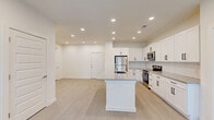 Located at 300 Commerce Ave in LaGrange, Georgia, this well-appointed single-story home offers three bedrooms, three bathrooms, and a thoughtfully designed layout that maximizes functionality and comfort. The heart of the home is an open-concept living, dining, and kitchen area bathed in recessed lighting and finished with light wood-look flooring. The kitchen stands out with crisp white shaker cabinetry, granite countertops with subtle speckled detailing, a classic subway tile backsplash, stainless steel appliances including a range, microwave, and refrigerator, and a central island with a built-in sink — ideal for both cooking and casual dining. The living area is bright and airy, with natural light streaming in through multiple windows. The generously sized primary bedroom features plush carpeting, a ceiling fan, and direct access to a walk-in closet with wire shelving. The primary bathroom offers a dual-sink vanity with granite countertops, a large mirror, and a tiled walk-in shower. Additional bedrooms are equally well-appointed, each with closet storage. A dedicated laundry room houses a full-size washer and dryer, adding everyday convenience. The home's clean, neutral palette and modern finishes create a cohesive and move-in-ready atmosphere throughout.