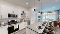 Located at 630 Washington Avenue in Belleville, NJ, this thoughtfully designed two-bedroom, two-bathroom residence offers a modern living experience with high-quality finishes throughout. The open-concept kitchen is a standout feature, showcasing white shaker cabinetry, stainless steel appliances, a mosaic tile backsplash, and a large center island with a quartz-style countertop and seating for four, illuminated by stylish pendant lights. The kitchen flows seamlessly into the living and dining areas, which benefit from large floor-to-ceiling windows that invite abundant natural light and provide views of the surrounding greenery. Wide-plank hardwood flooring runs throughout the space, adding warmth and continuity. The primary bedroom is a comfortable retreat, featuring a ceiling fan and direct access to a spacious walk-in closet outfitted with custom built-in shelving, hanging rods, and drawer units. The en-suite bathroom impresses with full-height grey tile, a glass-enclosed walk-in shower, and a backlit vanity mirror. The second bedroom also enjoys large windows with outdoor views. A second full bathroom features a soaking tub with grey tile surround and matte black fixtures, completing this well-appointed residence.
