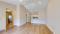 Located at 5260 Rogers Rd in Hamburg, NY, this single-floor home offers 3 bedrooms, 2 bathrooms, and a thoughtfully designed layout. The open-concept living and dining area is a standout, featuring soaring vaulted ceilings, recessed lighting, and light hardwood flooring that flows throughout. A fireplace with a white mantel anchors the living room, which is bathed in natural light from a sliding glass door leading to the outdoors. A ceiling fan adds comfort overhead. The kitchen is equipped with white cabinetry, granite-look countertops, tile flooring, and white appliances including a refrigerator, range, and built-in microwave. The two bathrooms feature tile flooring and granite-top vanities, with one including a tub/shower combo. The spacious primary bedroom is carpeted and includes a ceiling fan, while the additional bedrooms are similarly finished with carpet, ceiling fans, and windows offering outdoor views. A dedicated laundry area houses a stacked LG washer and dryer. The home also includes an attached garage, a utility room, four closets, and a hallway connecting the well-organized floor plan. Carpeted stairs with a wood handrail provide access to additional levels.