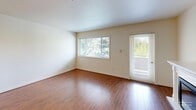 Located in Puyallup, WA, this single-floor, 3-bedroom, 2-bathroom home offers a well-organized layout designed for comfortable everyday living. The open-concept kitchen and living area serves as the heart of the home, where rich hardwood-style flooring runs continuously underfoot. The kitchen is well-appointed with warm maple cabinetry, a tiled backsplash, stainless steel appliances including a refrigerator, range, microwave, and dishwasher, and a peninsula island with a tile countertop. Track lighting overhead and pendant fixtures above the island provide ample illumination. The living area benefits from large windows and a sliding glass door that invite natural light and offer views of the surrounding greenery. The primary bedroom is generously sized, featuring hardwood-style flooring and large windows overlooking neighboring scenery. The additional bedrooms are carpeted, bright, and each include closet storage with built-in shelving. Both bathrooms are finished with tile flooring and warm wood vanities; the primary bath features a full tub-shower with decorative tile surround, while the secondary bath offers a clean, simple tub-shower combo. A utility room and hallway complete the functional floor plan of this well-maintained Puyallup home.
