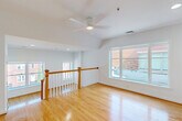 Located in the heart of Washington, DC, Unit 304 at 875 N St NW is a thoughtfully laid-out residence that maximizes its compact footprint with a clean, modern aesthetic. The open kitchen and living area serves as the central hub of the unit, featuring warm honey-toned hardwood floors that run throughout and crisp white walls that enhance the sense of brightness and space. The kitchen is well-appointed with light maple cabinetry, granite-look countertops, stainless steel appliances including a range, over-the-range microwave, dishwasher, and refrigerator, along with an in-unit stacked washer and dryer tucked conveniently nearby. The living area benefits from multiple windows that invite natural light and offer views of the surrounding neighborhood. A wood-railed staircase with white balusters adds an architectural accent and connects the living level to additional areas of the building. The hallway provides smooth circulation between the living spaces and the full bathroom, which is finished with large-format travertine-style floor and wall tiles, a wood-toned vanity with stone countertop, a framed mirror, and a glass-enclosed walk-in shower. The overall ambiance is clean, neutral, and move-in ready.