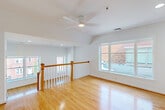 Located in the heart of Washington, DC, Unit 304 at 875 N St NW is a thoughtfully laid-out residence that maximizes its compact footprint with a clean, modern aesthetic. The open kitchen and living area serves as the central hub of the unit, featuring warm honey-toned hardwood floors that run throughout and crisp white walls that enhance the sense of brightness and space. The kitchen is well-appointed with light maple cabinetry, granite-look countertops, stainless steel appliances including a range, over-the-range microwave, dishwasher, and refrigerator, along with an in-unit stacked washer and dryer tucked conveniently nearby. The living area benefits from multiple windows that invite natural light and offer views of the surrounding neighborhood. A wood-railed staircase with white balusters adds an architectural accent and connects the living level to additional areas of the building. The hallway provides smooth circulation between the living spaces and the full bathroom, which is finished with large-format travertine-style floor and wall tiles, a wood-toned vanity with stone countertop, a framed mirror, and a glass-enclosed walk-in shower. The overall ambiance is clean, neutral, and move-in ready.