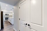 Located at 305 Timberland Drive in Ann Arbor, Michigan, this well-designed single-story home offers three bedrooms, two bathrooms, and a thoughtfully laid-out floor plan. The interior is finished with a clean, contemporary aesthetic featuring neutral tones, crisp white trim, and durable wood-look flooring throughout the main living areas.

The kitchen is a standout space, showcasing white shaker-style cabinetry with matte black hardware, granite countertops, stainless steel appliances, and a central island with pendant lighting — ideal for both cooking and entertaining. The open connection to the living area enhances the sense of space and flow.

The primary bedroom is generously sized and features plush carpeting, while its en-suite bathroom is appointed with a glass-enclosed walk-in shower, granite vanity, and matte black fixtures. A dedicated walk-in closet with built-in shelving provides ample storage. The secondary bathroom includes a shower-tub combination and a matching granite vanity with shaker cabinetry.

The additional bedrooms offer comfortable dimensions, with one featuring natural light from a window overlooking a green outdoor view. Hallways connect the spaces efficiently, and a utility room adds practical functionality. The home presents a move-in-ready, modern living experience throughout.