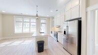 Located at 500 Carraway Crossing in Chapel Hill, NC, this single-floor residence offers a well-designed layout that balances openness with defined living spaces. A clean entry hallway with light hardwood-style flooring and crisp white trim leads directly into the heart of the home.

The kitchen serves as a central highlight, featuring floor-to-ceiling white shaker cabinetry with glass-front upper panels and a decorative wine rack detail. A large center island with an undermount sink and light countertops anchors the space, complemented by industrial-style pendant lighting. Stainless steel appliances, a textured tile backsplash, and multiple windows flooding the area with natural light complete the kitchen's polished, functional design.

Adjacent living areas are connected by distinctive sliding frosted-glass barn doors mounted on black hardware, adding a modern architectural touch. Recessed lighting and neutral warm-toned walls carry throughout the common spaces.

Bedrooms feature plush carpeting, generous natural light from large windows with blinds, and ample closet space, including both a spacious walk-in closet with wire shelving and a secondary closet with double panel doors.

The bathroom includes tile flooring, a soaking tub with subway tile surround, a separate glass-enclosed shower, and a white vanity with storage, offering a clean, spa-like atmosphere.