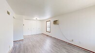 Located at 516 N Fourth St in Coleman, Michigan, this one-bedroom, one-bathroom unit offers a practical and efficient single-floor layout. The living room serves as the welcoming centerpiece of the space, featuring light gray luxury vinyl plank flooring, a large picture window with vertical blinds that invites natural light and offers views of the surrounding greenery, and a front entry door. A wall-mounted air conditioning unit provides convenient climate control. The kitchen is well-appointed with warm oak cabinetry spanning both upper and lower sections, generous white countertops in a U-shaped configuration, a double-basin stainless steel sink, and matching LVP flooring, offering ample storage and workspace. The bedroom is a cozy, carpeted room with a wood-trimmed window overlooking the outdoors, warm-toned baseboards, and a built-in closet for storage. A second room with additional closet space and its own wall unit provides versatile use. The bathroom includes a combination tub and shower, a single vanity with a vessel-style sink, a wall mirror, and LVP flooring, maintaining a clean and functional design. Throughout the unit, consistent warm wood accents in the trim and doors tie the aesthetic together, creating a cohesive and comfortable living environment.