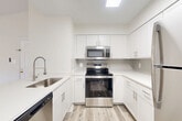 Located in Fairfax, VA, this thoughtfully designed one-bedroom, one-bathroom residence offers a bright and airy atmosphere throughout. Light-toned luxury vinyl plank flooring flows seamlessly across the entire space, complementing the crisp white walls and creating a clean, modern aesthetic.

The open-concept living and dining area serves as the heart of the home, featuring vaulted ceilings, a stylish chandelier, a cozy fireplace with a sleek dark surround, and multiple windows that flood the space with natural light. A sliding glass door opens directly onto a private balcony with outdoor views.

The kitchen is well-appointed with white shaker-style cabinetry, white quartz countertops, a subway tile backsplash, stainless steel appliances including a range, microwave, dishwasher, and refrigerator, as well as a stainless steel sink with a professional-style faucet. A peninsula counter connects the kitchen to the living area, enhancing the open flow. A dedicated pantry and in-unit laundry add practical convenience.

The spacious primary bedroom features generous closet storage and connects directly to the bathroom, which is outfitted with a full tub-shower combination and white vanity cabinetry. Two closets provide ample storage throughout the residence.