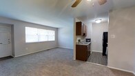 Located at 500 Chews Landing Road in Lindenwold, New Jersey, this single-floor unit offers a functional and comfortable layout designed for everyday living. The open-concept living area is finished with plush wall-to-wall carpeting that adds warmth underfoot, while neutral-toned walls create a clean, versatile backdrop throughout. A ceiling fan overhead provides both comfort and airflow, complementing the natural light that pours in through a large window, brightening the space throughout the day. The living area flows seamlessly into the kitchen, which is defined by rich dark wood cabinetry that provides ample storage. The kitchen is equipped with a sink set into a countertop, a black refrigerator, and a dishwasher, making it a practical and well-appointed space for cooking and meal preparation. The transition from carpeted living space to hard-surface kitchen flooring creates a clear and attractive visual separation between areas. The overall layout is efficient and thoughtfully arranged, offering a welcoming ambiance that balances comfort with practicality. This unit is well-suited for those seeking a low-maintenance, move-in-ready home in the Lindenwold area of southern New Jersey.