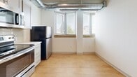 Located at 7150 Montview Blvd in Denver's vibrant 80220 neighborhood, this single-floor, 3-bedroom, 2-bathroom unit blends industrial character with modern finishes. Exposed metallic ductwork runs throughout the ceilings, creating a distinctive architectural element that complements the clean white walls and warm light hardwood flooring found in every room.

The kitchen is well-appointed with stainless steel appliances—including a range, microwave, and refrigerator—paired with gray shaker-style cabinetry, a subway tile backsplash, and a black matte sink. Large windows with blinds allow ample natural light to fill the kitchen and adjacent dining area, offering views of the surrounding neighborhood.

The three bedrooms are bright and functional, each featuring hardwood flooring, windows with blinds, and exposed ductwork consistent with the home's industrial aesthetic. The primary bedroom includes a walk-in closet with wire shelving. Both bathrooms are finished in white, with one offering a tub-shower combo, hardwood flooring, and a wall-mounted sink, while the second features classic hex tile flooring and an accessibility grab bar. A connecting hallway ties all rooms together in a linear, efficient layout.