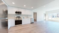 Located at The Skyline in West Sacramento, CA, this thoughtfully designed 4-bedroom, 2-bathroom residence offers a clean, modern aesthetic across a single level. Light-toned hardwood flooring runs seamlessly throughout, unifying every room and contributing to an airy, cohesive feel.

The open-concept kitchen and living area serves as the heart of the home. The kitchen is outfitted with full-height white flat-panel cabinetry, light countertops, a subway tile backsplash, and a complete suite of stainless steel appliances, including a refrigerator, range, microwave, and dishwasher. Recessed lighting illuminates the space with a clean, modern tone.

The four bedrooms are bright and well-proportioned, with neutral white walls and large windows that invite generous natural light. The spacious primary bedroom features a sliding door with outdoor access, flooding the room with sunlight and views of the surroundings. Bedrooms include closets with built-in wire shelving for practical storage.

The two bathrooms continue the home's minimalist palette, featuring white vanities with integrated sinks, large mirrors, brushed nickel fixtures, and hardwood-style flooring. One bathroom includes a full soaking tub, while the second offers a clean, functional layout. Together, these spaces reflect a cohesive, contemporary design ideal for modern living.