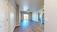This single-floor residence presents a clean, contemporary design highlighted by wood-look plank flooring that runs consistently throughout the space. The open living area is anchored by a ceiling fan and features a sliding glass door that opens to a private balcony, allowing natural light to fill the room and providing outdoor views of the surrounding neighborhood.

The kitchen is well-appointed with white shaker-style cabinetry extending to the ceiling, granite-look countertops, a tile backsplash, and a full suite of stainless steel appliances including a refrigerator, range, microwave, and dishwasher. Flush ceiling fixtures provide ample task lighting throughout the cooking space.

Multiple bedrooms are present, each finished with the same wood-look flooring, ceiling fans, and windows that invite natural light. The rooms offer generous wall space and closet access.

Two bathrooms serve the unit, each featuring white cabinetry, granite countertops, undermount sinks, and large mirrors. One bathroom includes a tub-shower combination, while the other offers a walk-in shower. Both are finished with light wood-look flooring and clean white walls, contributing to the space's bright, modern ambiance.