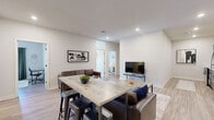 Located at 10 King Street in Troy, NY, this well-designed single-floor residence offers three bedrooms, two full bathrooms, a combined kitchen and living area, and a utility room — all within a thoughtfully organized layout. The open-concept living room provides generous space for relaxation, featuring recessed lighting, wood-look flooring, and a neutral color palette that creates a bright, welcoming atmosphere. The kitchen is a standout, equipped with slate-blue shaker cabinetry, white countertops, a subway tile backsplash, and a full suite of stainless steel appliances including a range, microwave, dishwasher, and refrigerator. The bedrooms are comfortably sized and well-lit, with one featuring large sliding glass doors that open to an outdoor balcony with urban views, and another offering a window with natural light and wood-look floors. Both bathrooms are cleanly finished with dark navy vanities, white countertops, and modern light fixtures above large mirrors. A dedicated utility room adds practical functionality to the residence. Throughout, consistent wood-look flooring, clean white walls, and modern fixtures create a cohesive, contemporary aesthetic suited for comfortable everyday living.