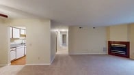 This single-floor residence offers a practical and comfortable layout designed for everyday living. The spacious living area is finished with neutral-toned wall-to-wall carpeting and features a textured ceiling, multiple HVAC vents, and a large sliding glass door fitted with vertical blinds that allows natural light to fill the room. A tiled entryway provides a clean transition from the front door into the carpeted living space.

The kitchen is efficiently arranged in an L-shaped configuration, featuring white cabinetry with warm wood trim, laminate countertops, a stainless steel sink, and white appliances including an electric range with overhead ventilation. Light hardwood-style flooring runs through the kitchen, lending warmth to the space.

A central hallway connects the living area to the private quarters, including well-proportioned bedrooms finished with carpet and clean walls. Two bathrooms serve the unit: one features a vanity with a large mirror, overhead lighting, and a walk-in shower, while the second includes a full bathtub/shower combo and hardwood-style flooring. A dedicated utility room houses the water heater and provides additional functional storage space, completing this straightforward and well-organized layout.