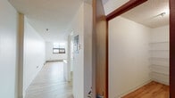 This single-floor residence offers a well-organized layout that balances functionality with a clean, understated aesthetic. The entry opens into a hallway with light wood-tone luxury vinyl flooring that extends throughout the main living areas, creating a cohesive and easy-to-maintain foundation underfoot.

The living area is generously proportioned, featuring large windows fitted with a wall air conditioning unit, baseboard heating, and a textured ceiling. Natural light filters in, brightening the neutral white walls throughout.

The kitchen is positioned in a semi-open configuration, separated from the living area by a half-wall pass-through that enhances the sense of connectivity. It is equipped with white cabinetry accented by wood-tone trim, a full suite of appliances including a refrigerator, electric range, dishwasher, and a double sink beneath under-cabinet lighting.

The bedroom is carpeted for comfort and includes a ceiling fan with integrated lighting, a window with an outdoor view, and baseboard heating. A full bathroom serves the unit, featuring light wood-tone vinyl flooring, a tub and shower combination with a handheld showerhead, a vanity, and clean white wall surrounds. Wood-tone doors with brushed hardware complete the interior details throughout.