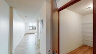 This single-floor residence offers a well-organized layout that balances functionality with a clean, understated aesthetic. The entry opens into a hallway with light wood-tone luxury vinyl flooring that extends throughout the main living areas, creating a cohesive and easy-to-maintain foundation underfoot.

The living area is generously proportioned, featuring large windows fitted with a wall air conditioning unit, baseboard heating, and a textured ceiling. Natural light filters in, brightening the neutral white walls throughout.

The kitchen is positioned in a semi-open configuration, separated from the living area by a half-wall pass-through that enhances the sense of connectivity. It is equipped with white cabinetry accented by wood-tone trim, a full suite of appliances including a refrigerator, electric range, dishwasher, and a double sink beneath under-cabinet lighting.

The bedroom is carpeted for comfort and includes a ceiling fan with integrated lighting, a window with an outdoor view, and baseboard heating. A full bathroom serves the unit, featuring light wood-tone vinyl flooring, a tub and shower combination with a handheld showerhead, a vanity, and clean white wall surrounds. Wood-tone doors with brushed hardware complete the interior details throughout.