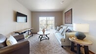 This 2-bedroom, 2-bathroom residence is thoughtfully designed across a single floor, offering a comfortable and cohesive living experience throughout. The open-concept kitchen features warm knotty wood cabinetry, granite-style countertops, and a full suite of black appliances including a refrigerator, range, microwave, and dishwasher. A pendant light illuminates the adjacent dining area, which comfortably accommodates a round dining table — ideal for everyday meals or casual entertaining. The living room is carpeted and inviting, anchored by a wall-mounted flat-screen TV and a sliding glass door that fills the space with natural light and provides access to an outdoor view. Both bedrooms are carpeted and offer open closet systems for easy organization. The primary bathroom is notably spacious, featuring rich wood cabinetry, granite-style countertops, a large vanity mirror, and durable wood-look vinyl flooring. The second bathroom mirrors the same quality finishes with a single-sink vanity and wood-look flooring. Neutral wall tones, warm wood trim, and consistent flooring materials throughout contribute to a cohesive, understated aesthetic that feels both functional and welcoming.