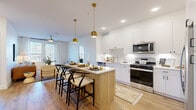 Located at 2960 Tutt Blvd in Colorado Springs, CO, this well-designed two-bedroom, two-bathroom residence offers a thoughtful single-level layout with a clean, contemporary aesthetic throughout. The open-concept kitchen and living area serves as the heart of the home, featuring crisp white cabinetry extending to the ceiling, stainless steel appliances including a gas range, microwave, dishwasher, and refrigerator, and a warm wood-toned kitchen island with seating for multiple guests. Elegant gold pendant lights hang above the island, adding a refined touch. Light hardwood flooring flows throughout the main living areas, complementing the bright, neutral color palette. The living room is a comfortable retreat with a ceiling fan and natural light filtering through windows. The primary bedroom offers a serene atmosphere with generous natural light, plush carpeting, a walk-in closet with built-in shelving, and direct access to a private en-suite bathroom. The en-suite features a double-sink vanity with white cabinetry, a framed mirror, and a glass-enclosed walk-in shower with tile surround. The second bedroom is equally well-appointed with its own closet access. Two dedicated closets provide ample storage throughout the residence, making this a highly functional and attractive living space.