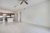 Located at 943 NW 97th Ave, Unit 211, in Miami, FL, this second-floor, 2-bedroom, 1-bathroom condominium encompasses 650 square feet of thoughtfully arranged living space. The kitchen is a standout feature, showcasing warm wood cabinetry, dark granite countertops with under-cabinet lighting, and stainless steel appliances including a range, microwave, and French door refrigerator. A center island with a matching granite top provides additional workspace. White porcelain tile flooring runs throughout the kitchen, while a dedicated laundry area with washer and dryer is conveniently accessible nearby. A louvered closet door provides additional storage along the hallway. The two bedrooms feature neutral carpet flooring and bright white walls. The primary bedroom spans 150 square feet, while both rooms offer windows with views of surrounding palm trees, allowing natural light to filter in. The bathroom is finished with tile flooring, a wood vanity with granite countertop, a bold framed mirror, and a full tub-shower combination. A private balcony overlooks a landscaped exterior with mature palm trees.