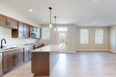 Located at 305 Timberland Drive in Ann Arbor, MI, this thoughtfully designed 1-bedroom, 1-bathroom home offers a bright and efficient single-floor layout. The open-concept living and kitchen area forms the heart of the home, where light hardwood-style flooring, recessed lighting, and multiple windows with white blinds create a clean, airy atmosphere. A glass-panel exterior door provides additional natural light and outdoor access.

The kitchen is a standout feature, showcasing rich dark wood cabinetry, granite countertops, a large central island ideal for dining or meal prep, and a full suite of stainless steel appliances including a refrigerator, range, microwave, and dishwasher. Stylish pendant lights hang above the island, adding a modern touch. The living room is generously sized with ample wall space and multiple windows offering views of the surrounding landscape.

The spacious primary bedroom is carpeted for comfort, benefits from two windows that invite natural light, and includes direct access to a dedicated walk-in closet. The bathroom features granite countertops, dark wood cabinetry with matte black hardware, and wood-look tile flooring, maintaining the cohesive design aesthetic found throughout the home.
