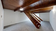 Located at 4412 Riverside Dr in Dayton, Ohio, this two-story unit offers two bedrooms and one bathroom across two equally sized floors, providing a well-balanced and functional layout. The space is defined by a standout architectural feature: rich, dark wood-planked ceilings with exposed beams on the lower level, which lend a warm, rustic character to the interior. A bold hardwood staircase with metal railing serves as a central design element, connecting both floors with visual impact.

The lower floor includes the kitchen, hallway, and staircase. The kitchen is equipped with warm wood cabinetry, granite-style countertops, a double-basin stainless steel sink, and a large window that brings in natural light. Flooring transitions from wood-style planks in the kitchen and hallway to carpet in the living areas.

Upstairs, two carpeted bedrooms offer comfortable living space. The primary bedroom is generously proportioned and includes access to a dedicated walk-in closet fitted with wire shelving. A second bedroom provides additional flexibility. The shared full bathroom features wood-tone cabinetry, granite-style countertops, and a tub-shower combination with clean white tile surround and hardwood-style flooring.