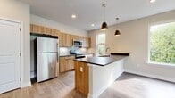 Located at 601 W Spruce St in Perkasie, PA, this thoughtfully designed 2-bedroom, 1-bathroom single-floor unit offers a clean, modern aesthetic with high-quality finishes throughout. Light-toned luxury vinyl plank flooring runs consistently across the space, complemented by crisp white walls and recessed lighting.

The open-concept kitchen and living area serves as the heart of the home. The kitchen is equipped with warm wood cabinetry, dark countertops, stainless steel appliances including a refrigerator, range, and microwave, and a central island with a built-in sink and pendant lighting above. Multiple large windows flood the space with natural light and offer views of surrounding greenery, while a ceiling fan adds comfort to the living area.

A clean hallway with panel-style doors connects the main living area to the private bedrooms and bathroom. The primary bedroom is generously sized, featuring multiple large windows with lush outdoor views and a ceiling fan. The second bedroom is bright and airy, with its own windows overlooking the trees. The full bathroom is finished with a wood-toned vanity, tub/shower combination, and coordinating flooring, maintaining the modern, neutral palette found throughout the home.