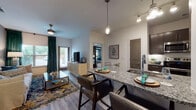 This single-story residence offers a thoughtfully designed open-concept layout connecting the kitchen, dining, and living areas. The kitchen is equipped with dark espresso cabinetry, stainless steel appliances including a French door refrigerator, granite countertops, a tile backsplash, and a breakfast bar with pendant lighting. Wood-style flooring flows throughout the main living areas, while a dedicated dining space accommodates a full table and chairs alongside direct sightlines to the kitchen.

The living room features neutral tones, a ceiling fan, and windows that invite natural light. Multiple bedrooms offer plush carpeting, large windows with blinds and draping curtains, and ceiling fans. One bedroom is notably appointed with a dramatic four-poster canopy bed frame and walk-in closet access.

Each bathroom reflects the home's consistent design language, featuring granite-topped dark vanities, wood-look tile flooring, and well-lit mirrors. The primary bath includes a glass-enclosed walk-in shower and direct access to a spacious walk-in closet with built-in rod storage. Overall, the space maintains a cohesive, contemporary aesthetic with neutral walls and teal accent tones throughout.