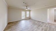 Located at 210 Hillwood Blvd in Murfreesboro, TN, this well-appointed 2-bedroom, 2-bathroom residence offers a thoughtfully designed single-floor layout. The open-concept living room features light wood-look flooring, crown molding, a ceiling fan with light fixture, and a glass door flanked by windows that invite natural light and outdoor views. The adjacent kitchen is equipped with stainless steel appliances—including a refrigerator, range, and microwave—complemented by gray cabinetry, a white quartz peninsula with an undermount sink, and tile flooring. Both bedrooms are carpeted and feature ceiling fans, crown molding, and windows with outdoor views. The primary bedroom includes a spacious walk-in closet with wire shelving for ample storage. The two bathrooms are finished with gray vanities, white quartz countertops, and wood-look tile flooring. One bathroom features a standard shower/tub combo, while the other boasts a jetted soaking tub with tiled surround. A dedicated in-unit laundry room accommodates a full-size washer and dryer with overhead wire shelving. The warm, neutral color palette and consistent finishes throughout create a cohesive and inviting atmosphere.
