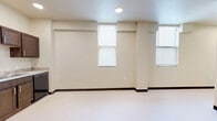 Located at 710 N Polk St in Amarillo, Texas, Unit 113 is a thoughtfully designed single-floor residence that makes efficient use of its cozy footprint. The open-plan living area is bathed in natural light through multiple double-pane windows fitted with horizontal blinds, lending the space a bright and airy feel. Light-toned flooring and neutral cream walls run throughout, creating a clean, cohesive aesthetic.

The kitchen is well-equipped with rich, dark wood cabinetry, black appliances including a range and refrigerator, a built-in range hood, and a sink with countertop workspace. Recessed lighting and a central ceiling-mounted HVAC unit keep the living and kitchen area comfortable and well-illuminated.

The bathroom features a full tub-shower combination with a curved curtain rod, a toilet, and a vanity with dark wood cabinetry and a light countertop, maintaining the consistent design language found throughout the unit.

A dedicated laundry area houses a stacked Whirlpool front-load washer and dryer alongside a water heater, providing practical in-unit convenience. A hallway connects the primary spaces, contributing to the unit's efficient and functional layout. Overall, the unit offers a clean, modern, and utilitarian living environment well-suited for comfortable day-to-day living.