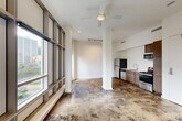Located in the heart of New Orleans' Central Business District, this modern one-bedroom, one-bathroom unit at 234 Loyola Ave offers a sleek, urban living experience across a single floor. The open-concept layout seamlessly combines the living, dining, and kitchen areas into one cohesive space, anchored by striking polished concrete floors with rich, mottled tones that flow throughout the entire unit.

The living area is bathed in natural light through an impressive wall of floor-to-ceiling grid-framed windows, offering views of the surrounding cityscape. A ceiling fan and recessed lighting complement the space, while a track lighting system provides additional illumination. Structural columns add an industrial character to the open floor plan.

The kitchen features warm wood cabinetry, a white subway tile backsplash, stainless steel appliances including a refrigerator, range, microwave, and dishwasher, and a clean countertop with an undermount sink.

The spacious primary bedroom includes its own floor-to-ceiling windows overlooking the city and a well-organized built-in closet. Three closets in total provide ample storage throughout the unit. The bathroom is finished with grey subway tile surrounding a soaking tub and shower combination, complemented by coordinating floor tile. A hallway connects the private areas of the unit to the main living space.