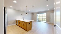 This thoughtfully designed one-bedroom, one-bathroom residence in Westfield, NJ offers a bright and contemporary living experience. The open-concept main area seamlessly integrates the kitchen, dining, and living spaces, all finished with light wood-style flooring and crown molding throughout. The kitchen is a standout feature, centered around a large island with a white quartz countertop, undermount sink, and stylish pendant lighting. Warm-toned wood cabinetry pairs elegantly with stainless steel appliances, including a French door refrigerator, gas range, and built-in microwave. The living area flows naturally toward a glass sliding door that opens to a private balcony, offering pleasant outdoor views and abundant natural light. The spacious bedroom also features a sliding glass door to the balcony, recessed lighting, and a generous closet. A second bedroom-sized room with large windows provides additional flexible living space. The bathroom is elegantly appointed with marble-style tile on both the floors and tub surround, a dual-sink vanity with a white quartz top, and a large mirror with modern lighting. Additional conveniences include in-unit laundry, hallway closets, and a well-organized layout that maximizes every square foot of this comfortable residence.