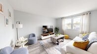 The Gilmore Renovated unit in Largo, Florida offers a thoughtfully updated single-floor layout comprising a living room, dining area, kitchen, bedroom, bathroom, hallway, and closet. Light gray walls and wood-look luxury vinyl flooring flow throughout the main living areas, creating a clean, cohesive aesthetic.

The living room is bright and welcoming, featuring a large window dressed with sheer curtains that allow natural light to fill the space. The adjacent dining area connects seamlessly to the kitchen, providing an open and functional flow ideal for everyday living.

The galley-style kitchen is well-appointed with crisp white cabinetry, stainless steel appliances including a refrigerator, range, and dishwasher, and a single-basin sink with modern fixtures. The layout maximizes efficiency while maintaining a bright, contemporary feel.

The generously sized bedroom is finished with plush wall-to-wall carpet, vertical blinds offering privacy, a ceiling fan with light fixture for year-round comfort, and a built-in closet with bi-fold doors providing ample storage.

The bathroom features a white vanity with updated hardware, a large mirror, modern light bar, and a tiled tub/shower combination, all finished with wood-look tile flooring for a polished look. This renovated unit combines practicality with modern design throughout.