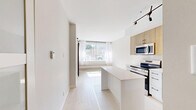 Located at 331 Metcalfe St in Ottawa's vibrant Centretown neighbourhood, this one-bedroom, one-bathroom unit offers a thoughtfully designed layout that maximizes every square foot. The modern kitchen is a standout feature, showcasing light wood upper cabinetry paired with crisp white lower cabinets, quartz countertops, a central island, and a full suite of stainless steel appliances including a range, built-in microwave, dishwasher, and refrigerator. A contemporary multi-arm track light fixture adds a stylish touch overhead. The open layout allows natural light to flow from the living area into the kitchen, enhancing the bright, airy atmosphere throughout. The bedroom is an intimate, quiet space with light hardwood-style flooring, neutral walls, and a large window fitted with sheer curtains that frame a view of lush greenery outside. A baseboard radiator ensures comfortable heating. The bathroom features clean white tile, a full soaking tub with shower, large-format floor tiles, and a white vanity, all accented with matte black fixtures for a modern contrast. The overall aesthetic throughout the unit is clean, contemporary, and functional — ideal for those seeking efficient urban living in the heart of Ottawa.