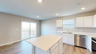 Located in Elkhorn, Nebraska, this well-appointed three-story home offers five bedrooms, four bathrooms, and a thoughtfully designed layout spread across three distinct floors. The entry level provides a compact yet functional footprint, while the main living floor expands to accommodate the heart of the home. The upper floor is the most expansive, housing the majority of the bedrooms and closets.

The open-concept kitchen and living area is a standout feature, highlighted by crisp white cabinetry, light quartz countertops, a central island, and stainless steel appliances including a range, microwave, dishwasher, and refrigerator. Light hardwood-style flooring runs throughout, and a sliding glass door opens to an outdoor deck with open views of the surrounding landscape.

The five bedrooms offer a mix of hardwood-style and plush carpeted flooring, with ample natural light from well-placed windows. The primary bedroom is generously sized and accompanied by dedicated closet space. The four bathrooms are clean and modern, featuring sliding glass shower enclosures, white vanities, and wood-tone flooring.

A dedicated laundry room houses a full-size washer and dryer with overhead shelving. Additional highlights include multiple closets throughout, convenient hallway connections between rooms, and a lower-level space with soft carpet — ideal for a recreational or flex room.