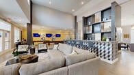 This stylish single-floor community clubhouse is designed to offer residents a comprehensive amenity experience within a contemporary, open-concept layout. Soaring ceilings with recessed lighting define the main gathering area, which flows seamlessly between distinct functional zones. The expansive lounge features generous sectional seating, plush area rugs, and large windows with views of the outdoor pool area, filling the space with natural light. Decorative wall art and metallic accent pieces reinforce a cohesive modern aesthetic throughout. A dedicated game room accommodates a full-size billiards table alongside wall-mounted flat-screen televisions and additional seating, making it ideal for social gatherings. The well-appointed wet bar area is equipped with granite countertops, custom cabinetry with gold hardware, a draft beer tap, and under-counter appliances, providing a full entertaining hub. A private meeting or dining room offers a refined setting with a wood-topped table, designer pendant lighting, and curated artwork. The leasing or concierge area near the entrance includes a dedicated desk and display shelving. Polished concrete flooring runs throughout, grounding the space with a clean, durable finish that complements the warm neutral tones and contemporary furnishings found across every area.